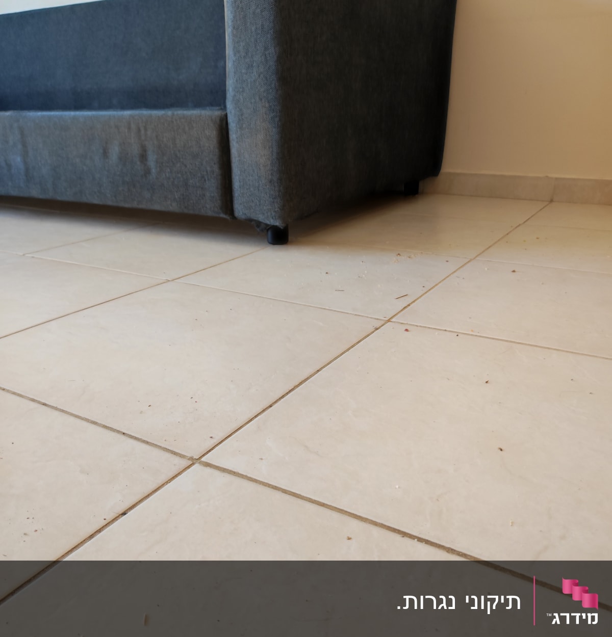 רצפת אריחים עם לכלוך קל ליד ספה אפורה